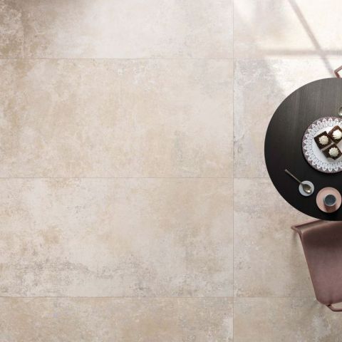 Hochwertige Beige-Naturstein-Bodenfliesen im modernen Wohnambiente mit Möbeln Elegante Beige-Fliesen mit schwarzem Tisch, Desserts und Getränken auf dekorativem Teller